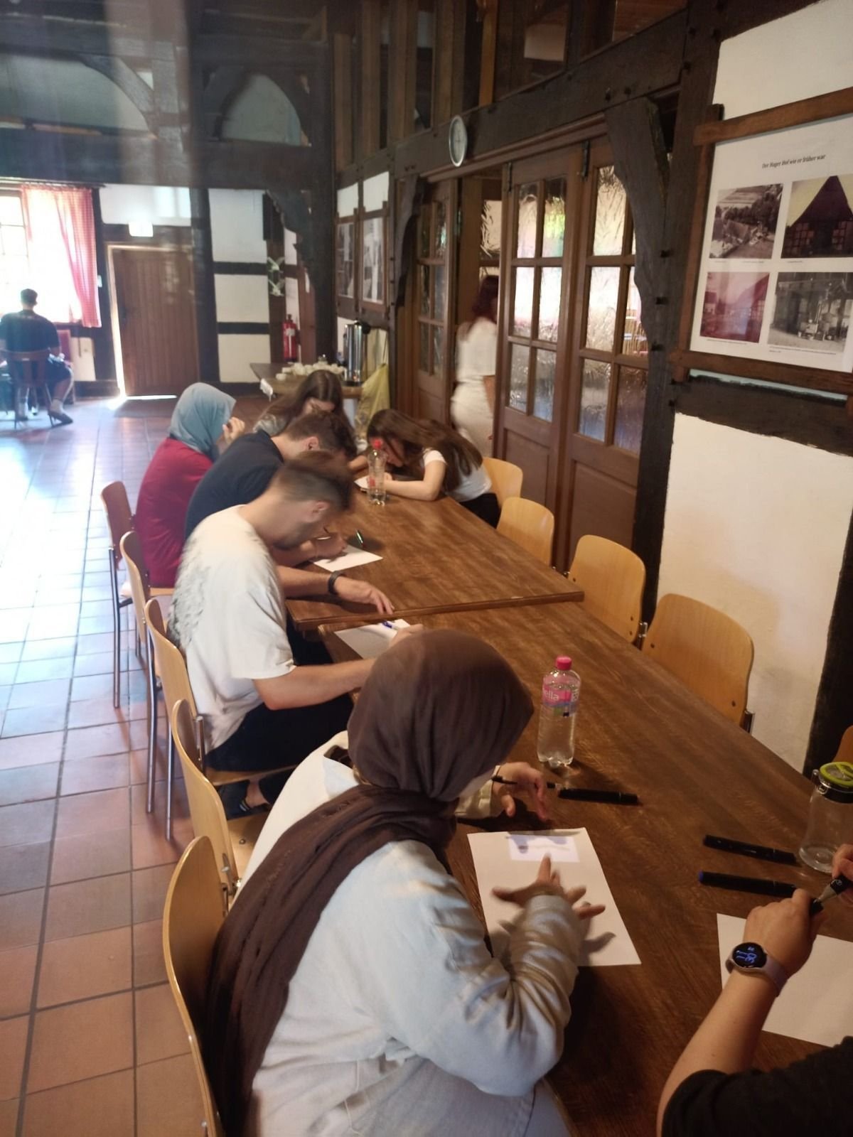 Teilnehmende arbeiten gemeinsam an einer langen Tischreihe während einer Workshop-Übung